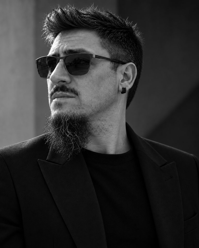 Aleksandar Žeželj in a black suit and sunglasses against a concrete wall.